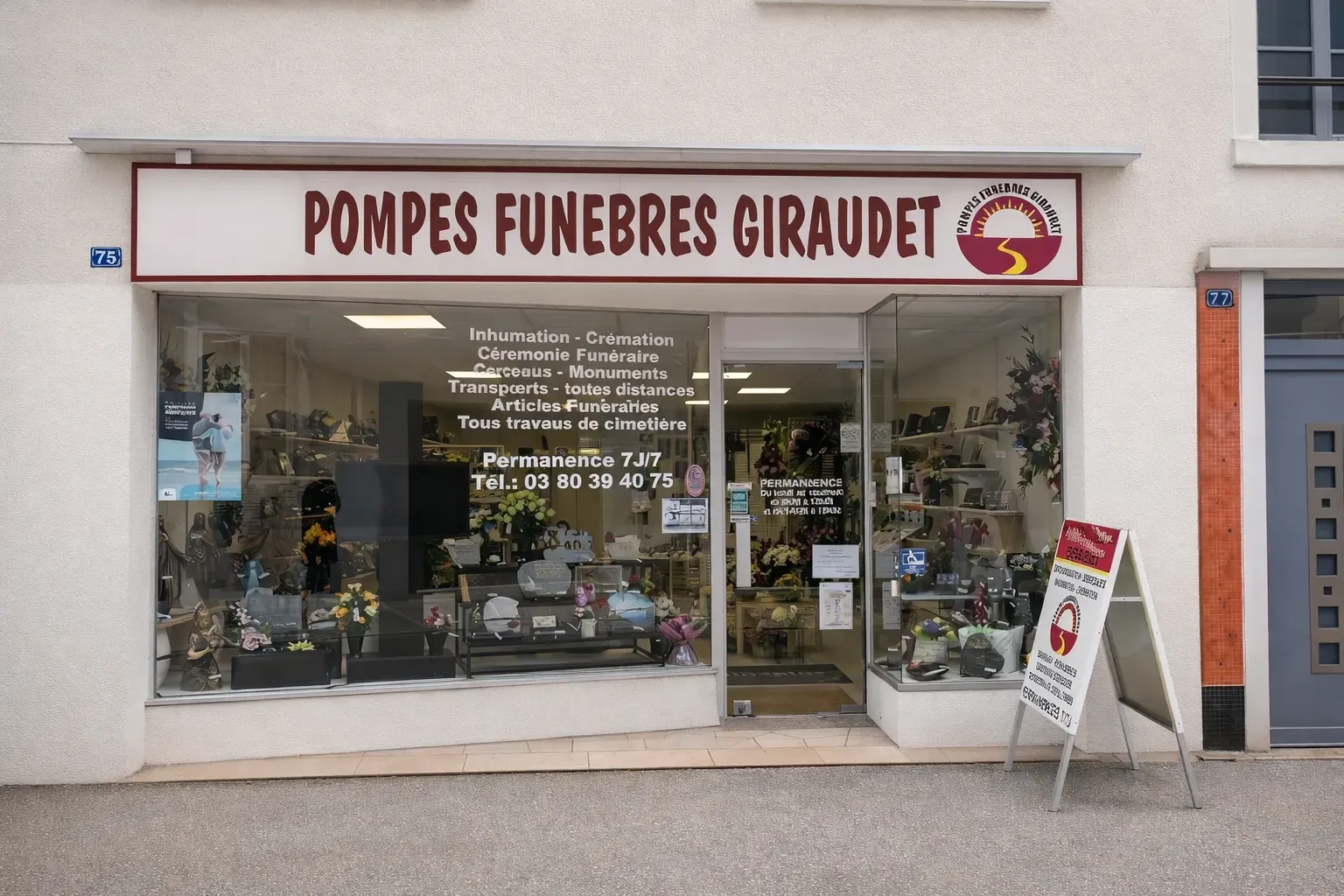 Devanture de l'agence Pompes Funèbres Giraudet avec vitrine d'articles funéraires.