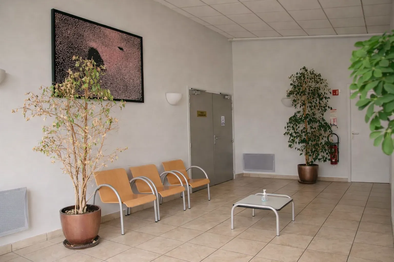 Salle d'attente lumineuse et aménagée de la chambre funéraire avec chaises en bois.