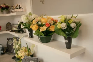 Fleurs artificielles funéraires en pot sur une étagère, pour la Toussaint et les obsèques.