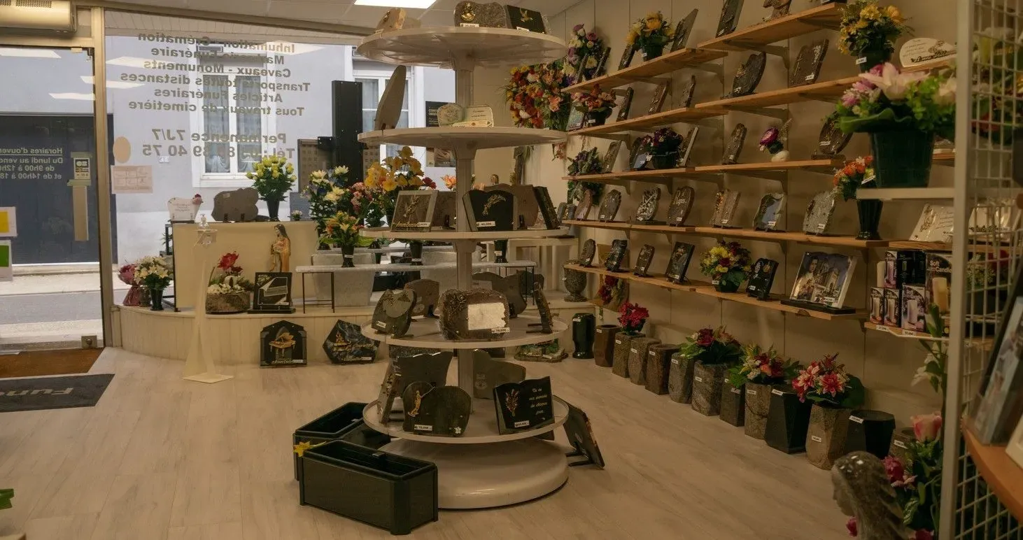 Intérieur d'un magasin funéraire avec stèles, plaques et fleurs de souvenir.